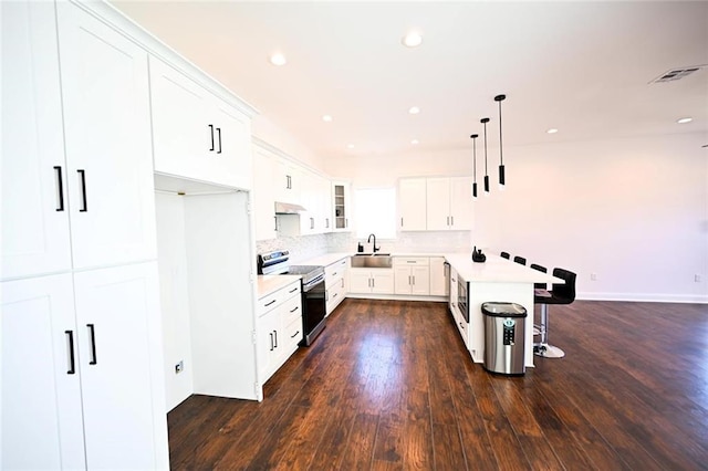 kitchen featuring a kitchen breakfast bar, dark wood-type flooring, stainless steel electric range, decorative light fixtures, and white cabinetry