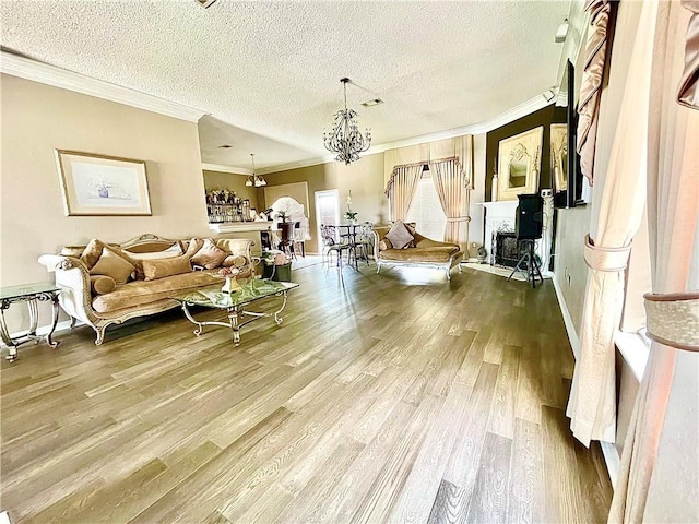 living room with hardwood / wood-style floors, a textured ceiling, ornamental molding, and a notable chandelier