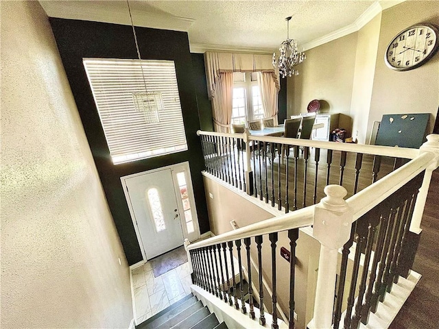 staircase with hardwood / wood-style flooring, crown molding, a textured ceiling, and a chandelier