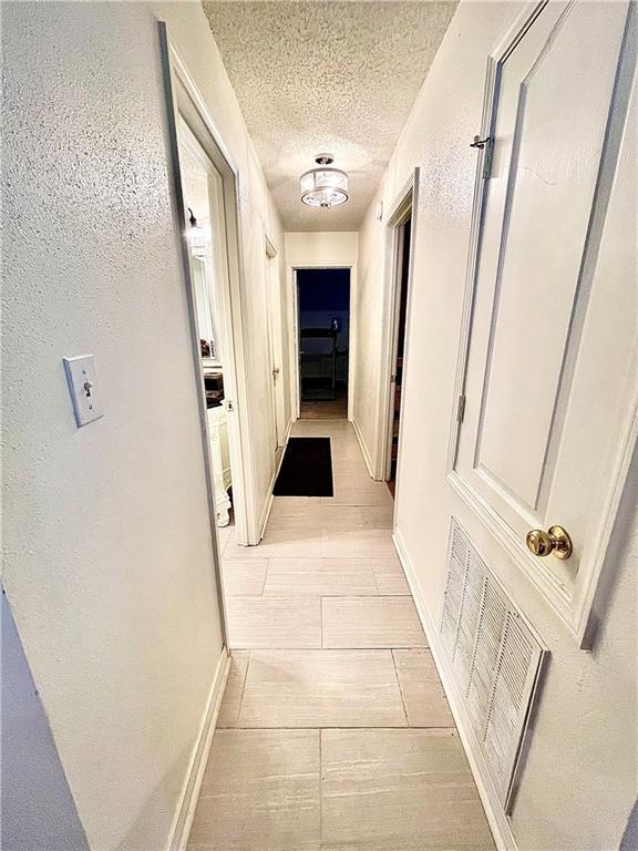 corridor with light hardwood / wood-style floors and a textured ceiling