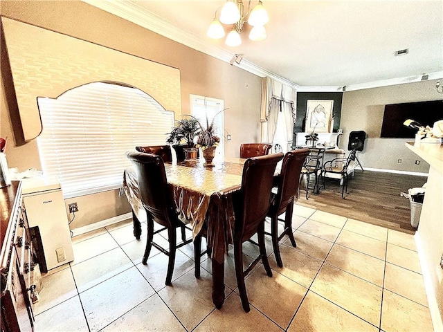 tiled dining space with crown molding and a chandelier