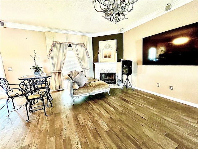 living area with a chandelier, hardwood / wood-style floors, a textured ceiling, and ornamental molding