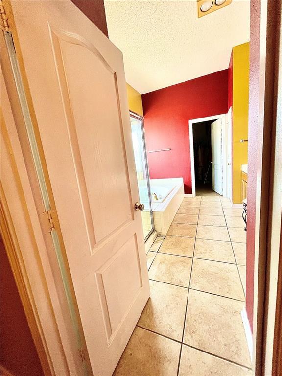 bathroom featuring tile patterned floors, a textured ceiling, and tiled tub