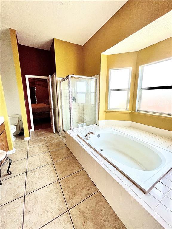 bathroom with tile patterned flooring, independent shower and bath, and toilet