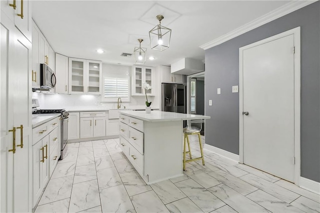 kitchen featuring appliances with stainless steel finishes, a kitchen island, white cabinetry, decorative light fixtures, and a breakfast bar