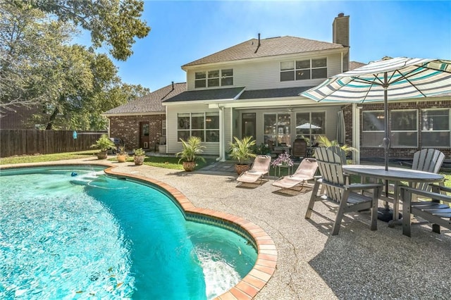 rear view of property featuring a fenced in pool and a patio area