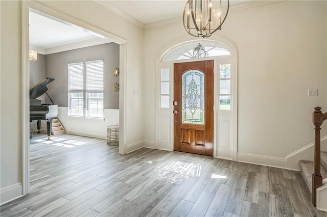 foyer entrance with ornamental molding, wood finished floors, baseboards, stairway, and a notable chandelier