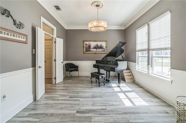 living area with crown molding, wood finished floors, and visible vents