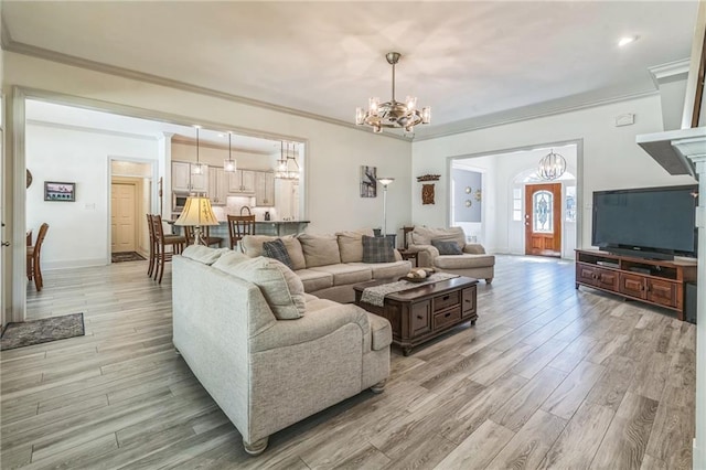 living room featuring an inviting chandelier, baseboards, ornamental molding, and light wood-style floors