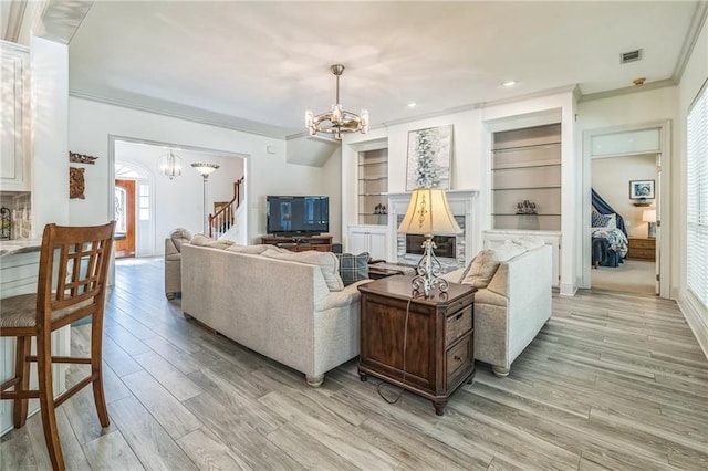 living area featuring an inviting chandelier, ornamental molding, visible vents, stairway, and light wood-type flooring