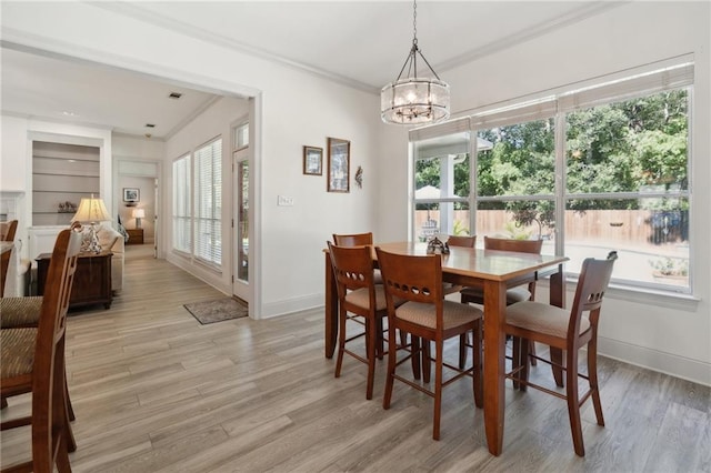 dining space featuring light hardwood / wood-style floors, crown molding, built in features, and an inviting chandelier