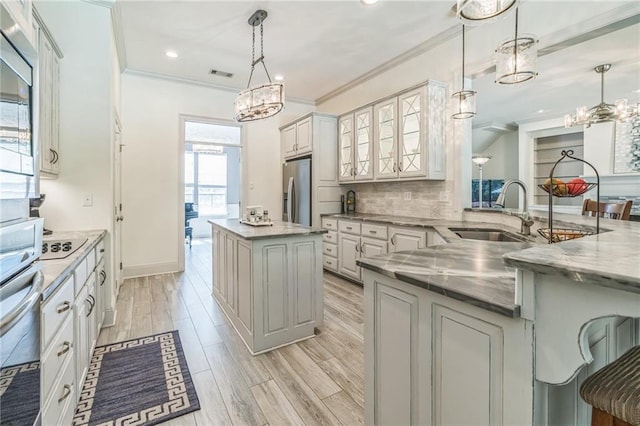 kitchen featuring light hardwood / wood-style flooring, sink, decorative light fixtures, appliances with stainless steel finishes, and tasteful backsplash