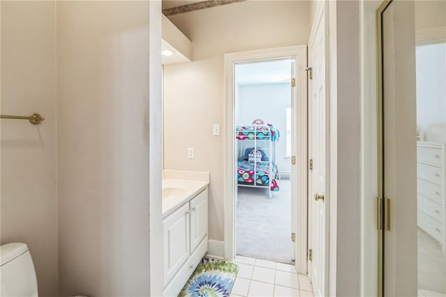 half bathroom with toilet, baseboards, tile patterned flooring, and vanity