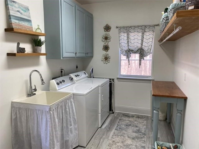 laundry area with light wood-type flooring, washer and clothes dryer, cabinet space, and baseboards