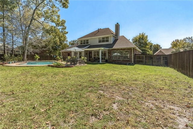 back of house featuring a lawn, brick siding, a fenced backyard, and a patio area