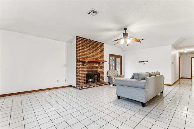 tiled living room with a textured ceiling, ceiling fan, and a fireplace