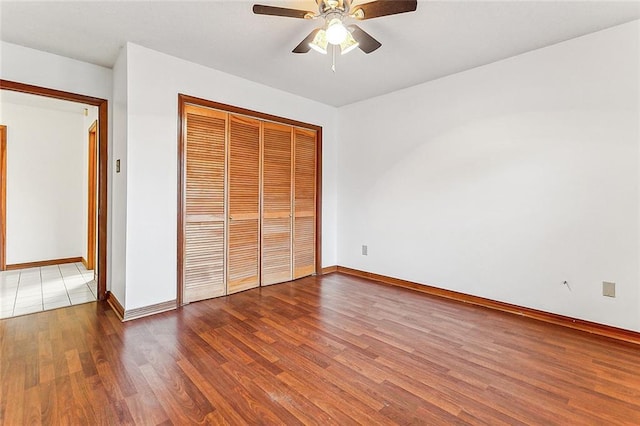 unfurnished bedroom with ceiling fan, wood-type flooring, and a closet