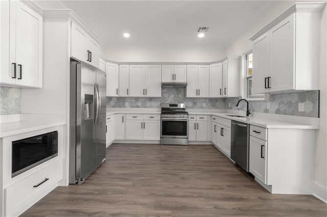 kitchen with sink, dark wood-type flooring, appliances with stainless steel finishes, and white cabinetry