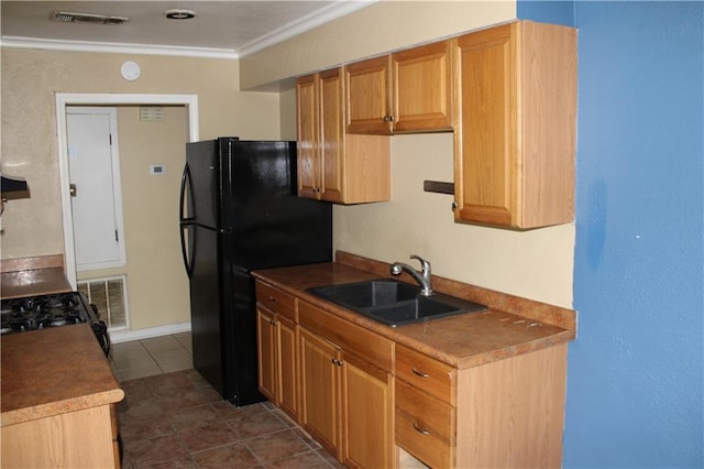 kitchen with dark tile patterned flooring, crown molding, sink, and black fridge