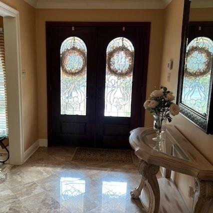 foyer featuring french doors and ornamental molding