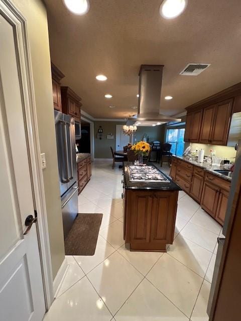 kitchen featuring appliances with stainless steel finishes, an inviting chandelier, island range hood, light tile patterned flooring, and a center island