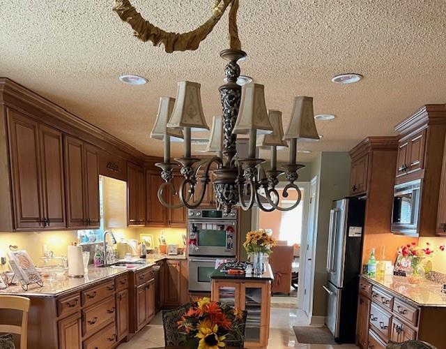 11051 Lake Forest Blvd, New Orleans, LA 70127 - kitchen featuring a notable chandelier, stainless steel appliances, a textured ceiling, and a sink