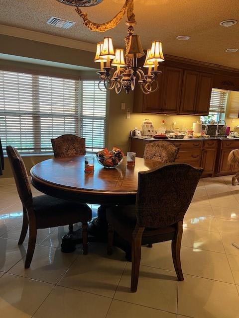 tiled dining area with sink, a textured ceiling, a chandelier, and plenty of natural light