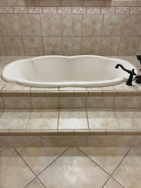 bathroom with a relaxing tiled tub and tile patterned floors