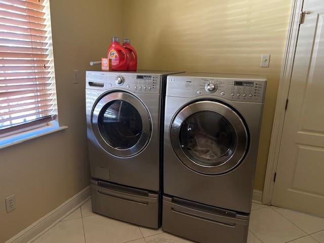 11051 Lake Forest Blvd, New Orleans, LA 70127 - laundry area featuring light tile patterned floors, baseboards, washer and dryer, and laundry area