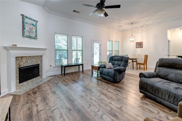 living room featuring hardwood / wood-style floors, crown molding, a fireplace, and ceiling fan