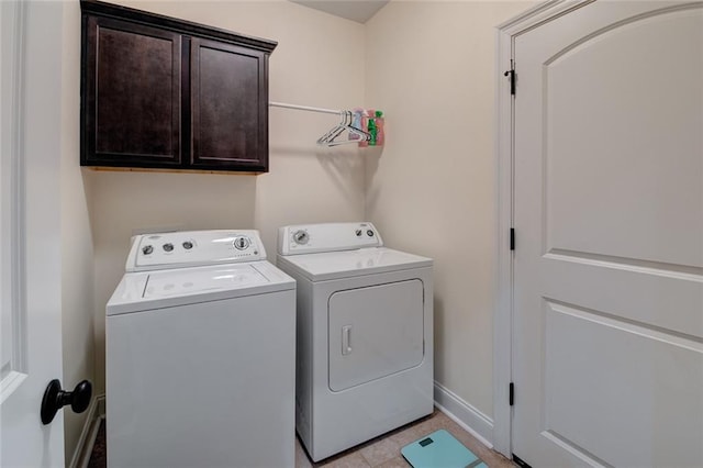 washroom with washing machine and clothes dryer, light tile patterned floors, and cabinets