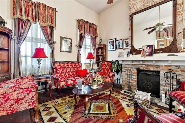 living area with ceiling fan, a brick fireplace, and hardwood / wood-style floors