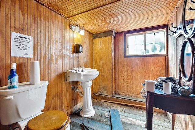 bathroom featuring toilet and wood walls