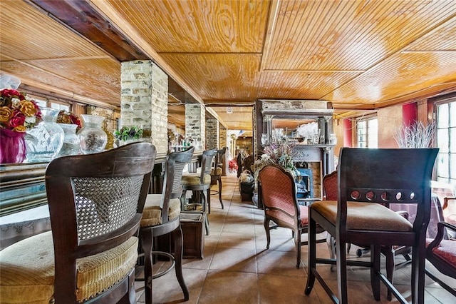 living area with decorative columns, wood ceiling, and tile patterned flooring