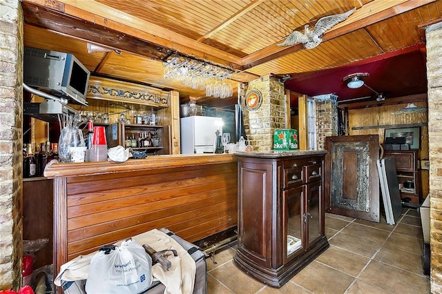 bar with wooden walls, wood ceiling, tile patterned flooring, and white refrigerator