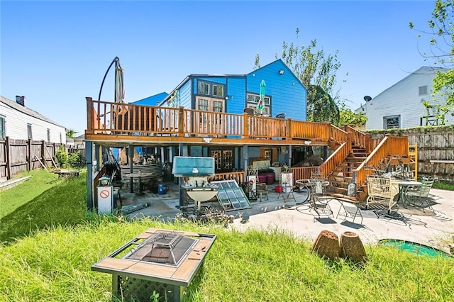 rear view of property featuring a patio area, a deck, a lawn, and an outdoor fire pit