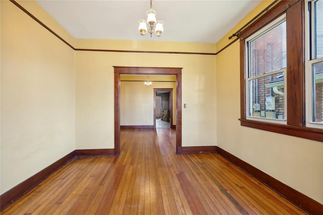 unfurnished room with hardwood / wood-style floors and an inviting chandelier