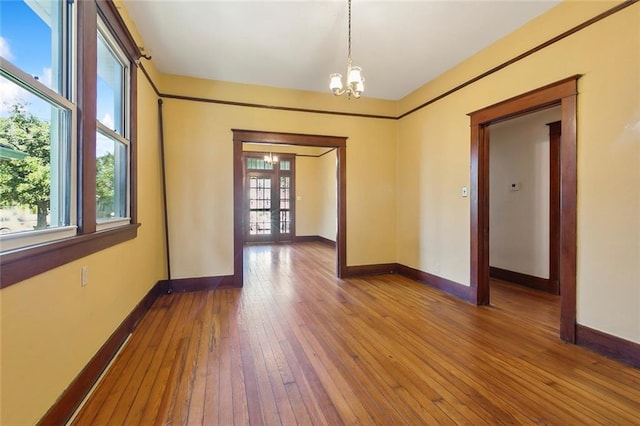 unfurnished room with french doors, a notable chandelier, and hardwood / wood-style flooring