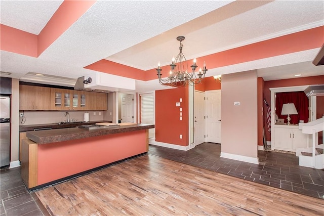 64 Fairway View Dr Unit 1, Hammond, LA 70401 - kitchen with a notable chandelier, brown cabinetry, baseboards, dark countertops, and a textured ceiling