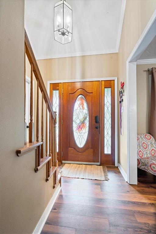 entrance foyer featuring ornamental molding, hardwood / wood-style flooring, and a chandelier