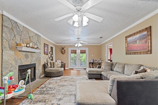 living room with a fireplace, wood-type flooring, ceiling fan, and crown molding