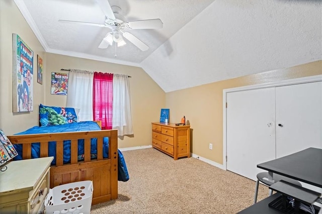 bedroom with ornamental molding, ceiling fan, light colored carpet, a closet, and vaulted ceiling