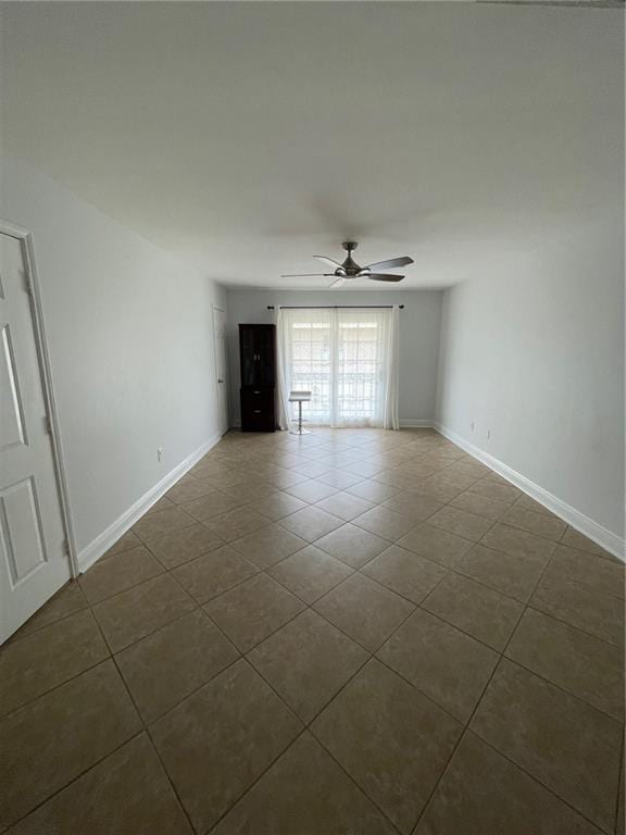 unfurnished room featuring ceiling fan and dark tile patterned floors