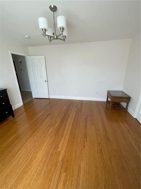 unfurnished room with hardwood / wood-style floors and an inviting chandelier