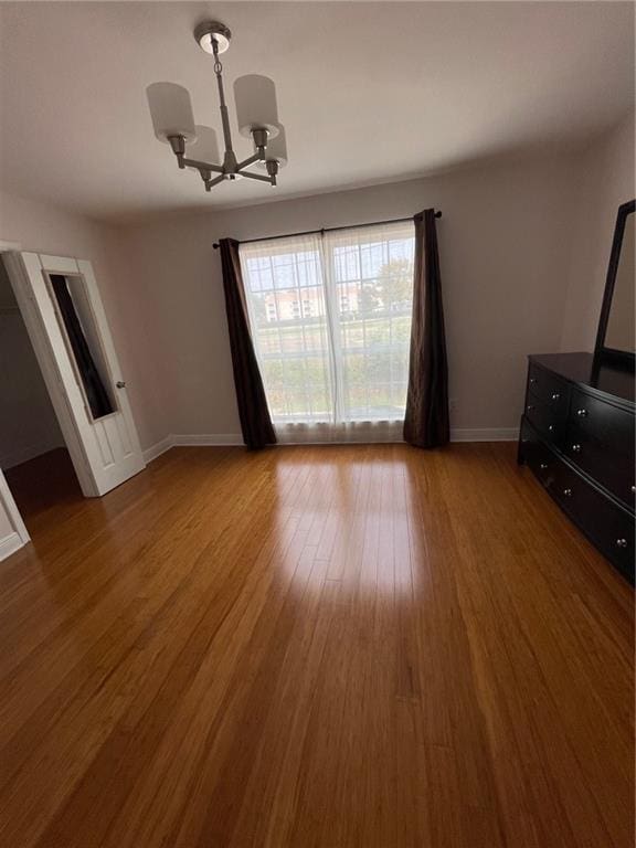 unfurnished dining area featuring a chandelier and wood-type flooring