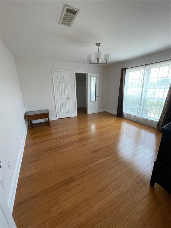 spare room with hardwood / wood-style floors and a chandelier