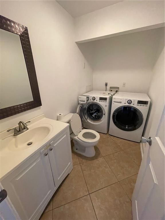 washroom with light tile patterned floors, sink, and washing machine and clothes dryer