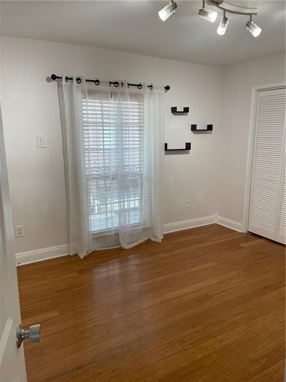 spare room featuring track lighting and wood-type flooring