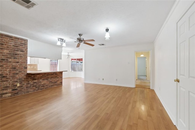 unfurnished living room with ornamental molding, ceiling fan, light wood-type flooring, and brick wall