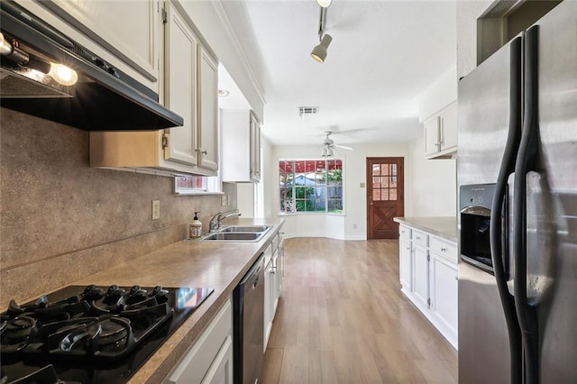 kitchen with appliances with stainless steel finishes, sink, light wood-type flooring, and white cabinets